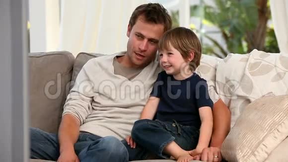 细心的父亲和儿子一起看电视视频的预览图