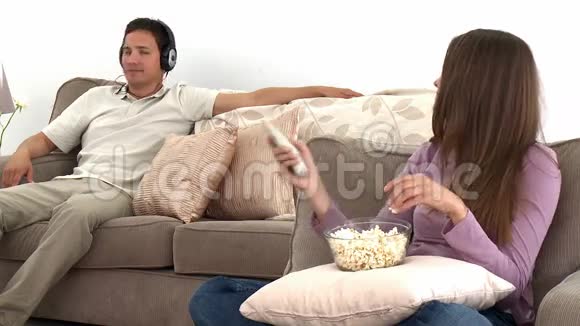女人用爆米花看电视而她的丈夫听音乐视频的预览图