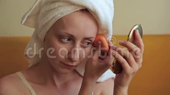 美丽的年轻女人用遮瑕霜化妆视频的预览图