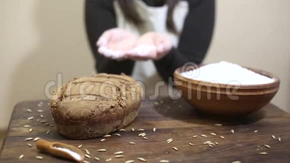 面包师把面粉吹到刚出炉的自制有机酸面团黑麦面包上放在木桌上视频的预览图