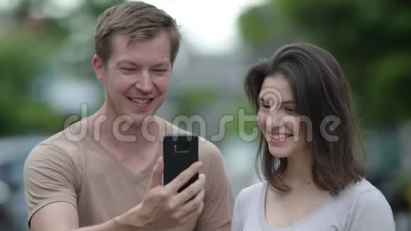 年轻的幸福夫妇在户外的大街上一起用电话视频的预览图
