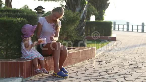 母亲在公园用饭盒喂女儿水果视频的预览图