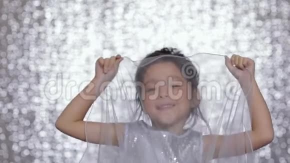 可爱快乐的小女孩穿着银色的裙子在银色的背景下跳舞视频的预览图