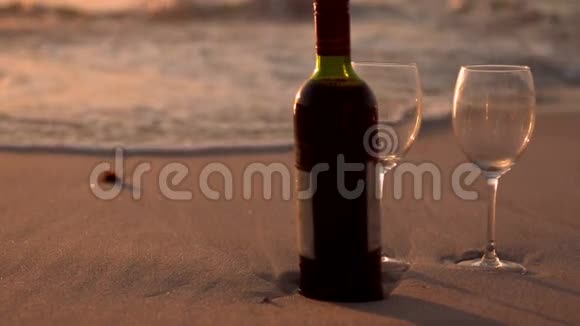 沙滩上的红酒瓶和酒杯视频的预览图