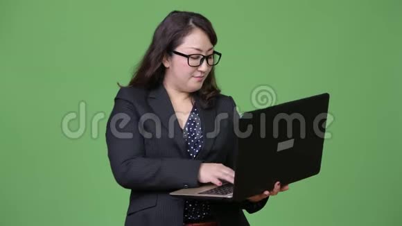 成熟漂亮的亚洲女商人绿色背景下使用笔记本电脑视频的预览图