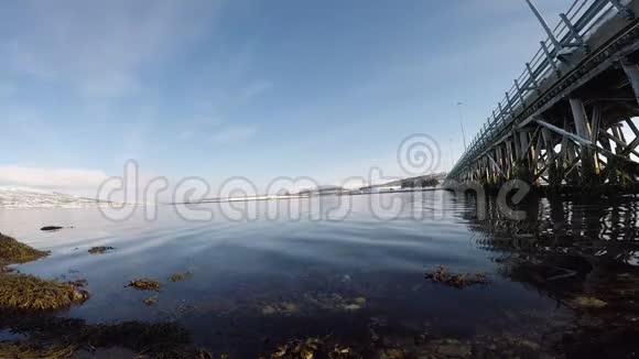 古老的木桥下腹部覆盖着古老的藤壶有平静的海浪和阳光视频的预览图