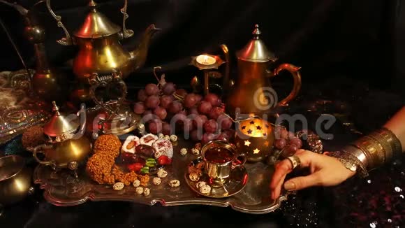 有东方珠宝店的女人喝茶吃传统的摩洛哥糖果萨弗龙马萨拉奶茶杯视频的预览图