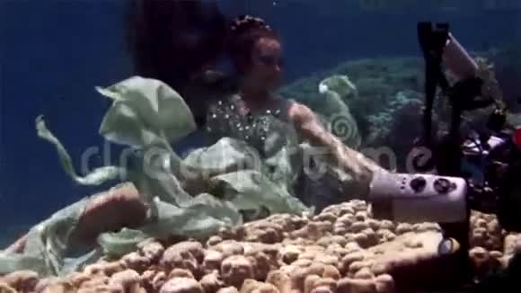 水下模型自由潜水员在红海珊瑚的背景上为相机拍照视频的预览图