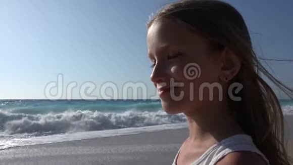 日落海滩上的儿童嬉戏看海浪的儿童沙滩上的女孩肖像视频的预览图