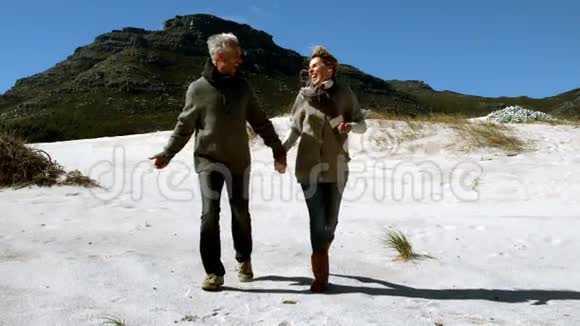 无忧无虑的成熟夫妇手牵手在海滩上奔跑视频的预览图