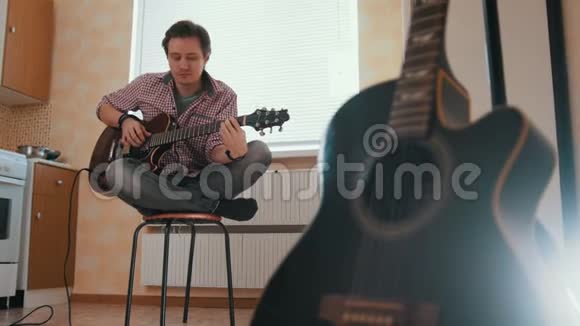 年轻的音乐家用吉他作曲在厨房里演奏其他乐器在前台视频的预览图