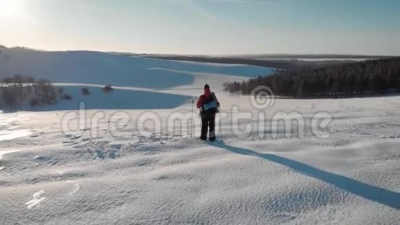 一个人背着背包背着跋涉的棍子在冬天的群山背景下美丽的日落山上的雪A视频的预览图