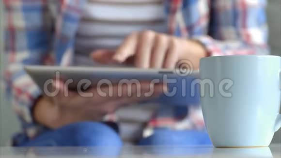 与使用平板电脑的女士同桌的咖啡杯视频的预览图