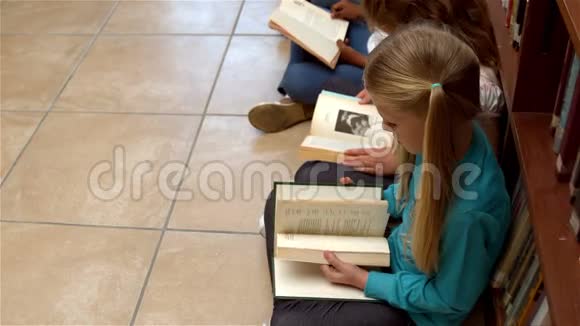 坐在图书馆地板上看书的可爱的学生视频的预览图