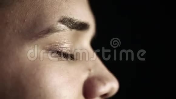 一个绿眼睛黑背景的年轻人的特写侧脸视频的预览图