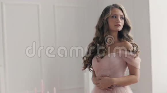 穿着粉色婚纱穿着经典大厅的美丽黑发女孩视频的预览图