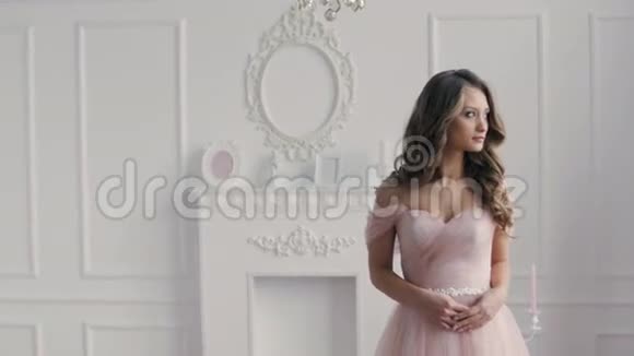 穿着粉色婚纱穿着经典大厅的美丽黑发女孩视频的预览图