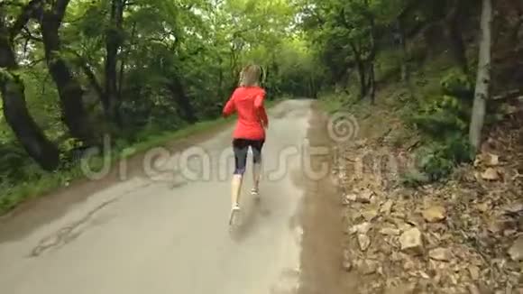 奔跑的女孩在夏季森林里做户外运动的金发女孩后视慢动作广角视频的预览图