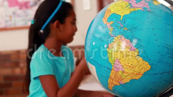 小女孩看地球仪在教室里写作视频的预览图