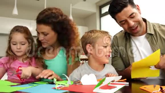 快乐的父母和孩子们在餐桌上做工艺品视频的预览图