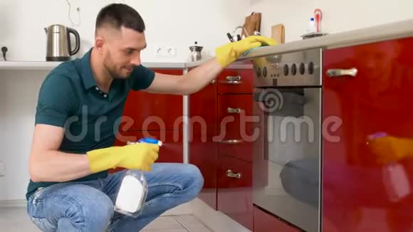 一个带抹布的人在家厨房里打扫烤箱门视频的预览图
