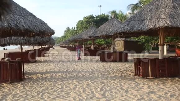 穿着长裙的女孩在沙滩上遮阳伞摆姿势视频的预览图