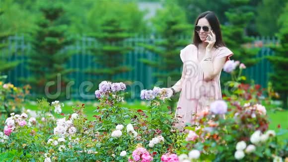 美丽的玫瑰花丛中花园里的小女孩玫瑰的气味视频的预览图