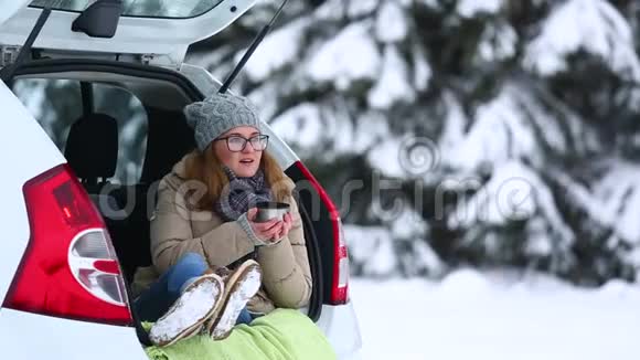 女旅行者坐在汽车的后备箱里视频的预览图