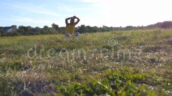年轻男子坐在瑜伽姿势在草地上的绿草和冥想肌肉男在莲花中放松的姿势视频的预览图
