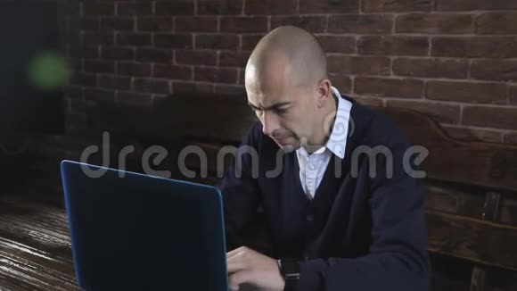 一位作家在笔记本电脑上靠砖墙写小说视频的预览图