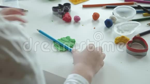 一个小女孩玩橡皮泥滚球桌面上有图形和彩色铅笔发展视频的预览图
