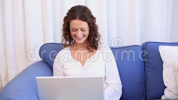 快乐的女人在沙发上用笔记本电脑接电话视频的预览图