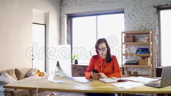 女商人在办公室里用她的智能手机视频的预览图