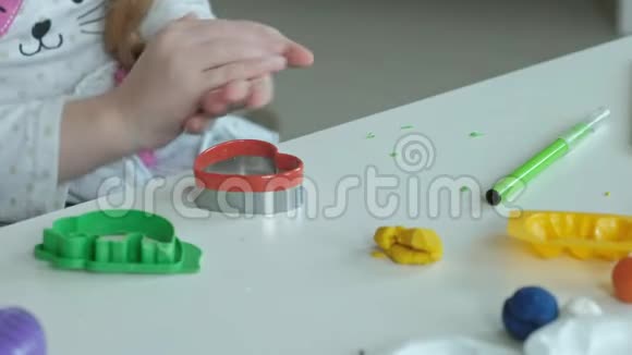 一个小女孩玩橡皮泥滚球桌面上有图形和彩色铅笔发展视频的预览图