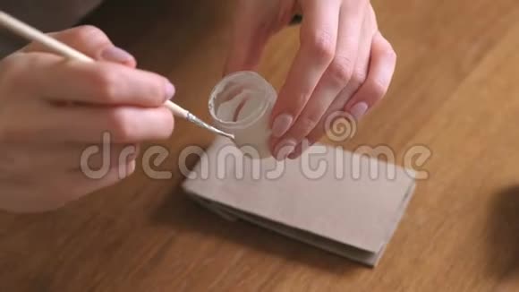 女人为孩子们制作圣诞来临日历用刷子和白色油漆在袋子上写一个数字特写双手视频的预览图