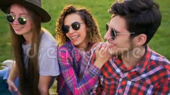 四个嬉皮士坐在草地上野餐视频的预览图