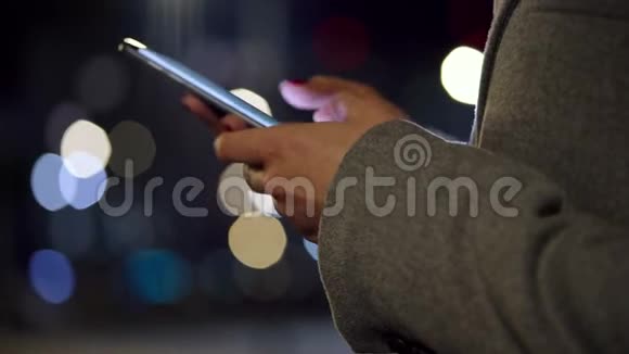 女性手使用智能手机模糊城市灯光背景视频的预览图