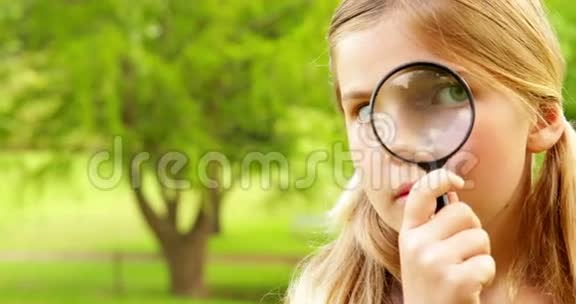 可爱的小女孩在公园里用放大镜视频的预览图