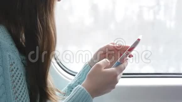 年轻女孩坐火车和使用手机漂亮的女人从智能手机上发送信息女性视频的预览图