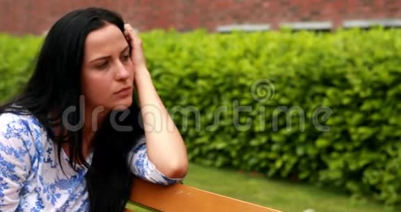 伤心的黑发女人在公园的长椅上思考视频的预览图