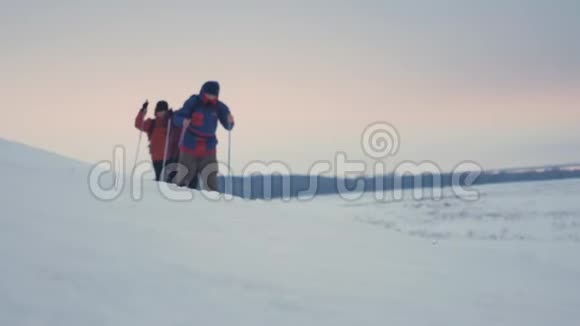 三个徒步旅行者带着徒步旅行杆一个背包和雪鞋徒步旅行者小组冬季旅行愉快视频的预览图