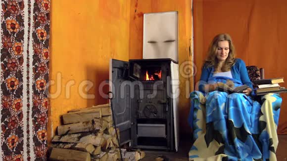 寒冷的冬天女人坐在扶手椅上看书放大视频的预览图