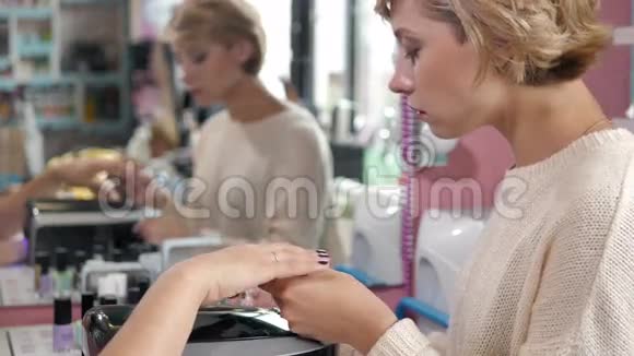 一个美甲沙龙里的女人接受美容师的指甲修剪女人正在修指甲美容师档案视频的预览图