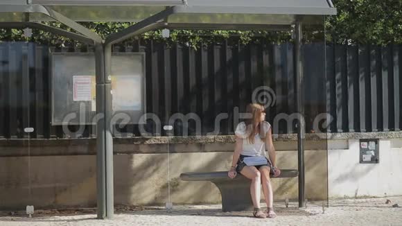 孤独的少女穿着裙子在公共汽车站等候视频的预览图