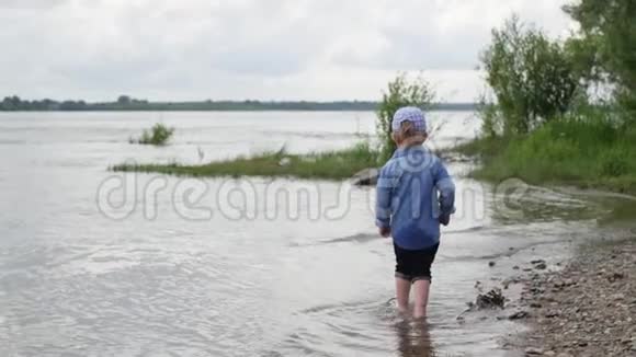 小男孩沿着河走那孩子在湖边跑慢动作快乐的婴儿在水边玩耍视频的预览图
