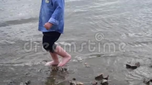 小男孩沿着河走那孩子在湖边跑慢动作快乐的婴儿在水边玩耍宝贝视频的预览图