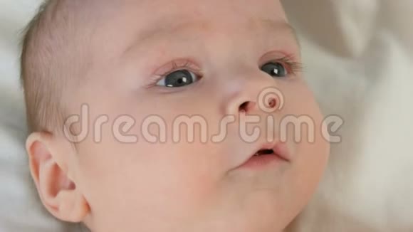 躺在白床上的两个月小婴儿的美丽滑稽肖像视频的预览图