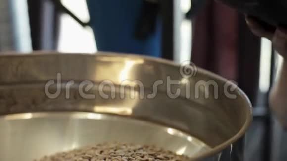 工人在咖啡厂的大铝圆桶里加入不炸咖啡颗粒视频的预览图