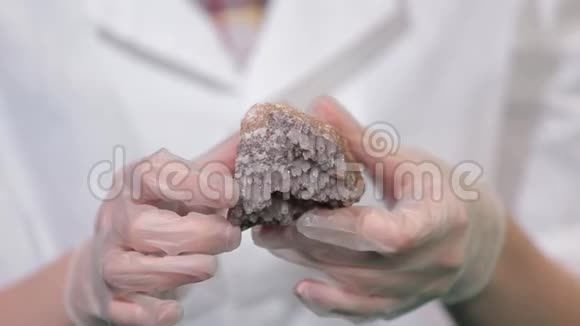 戴着手套手里拿着明亮的灰色红宝石水晶矿石结晶是固体的自然或人工过程视频的预览图