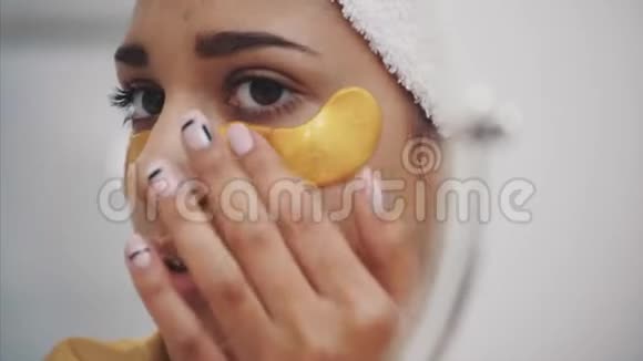 一幅美丽女人洗澡后用毛巾在头上的特写肖像将皱纹贴在眼睛下面视频的预览图